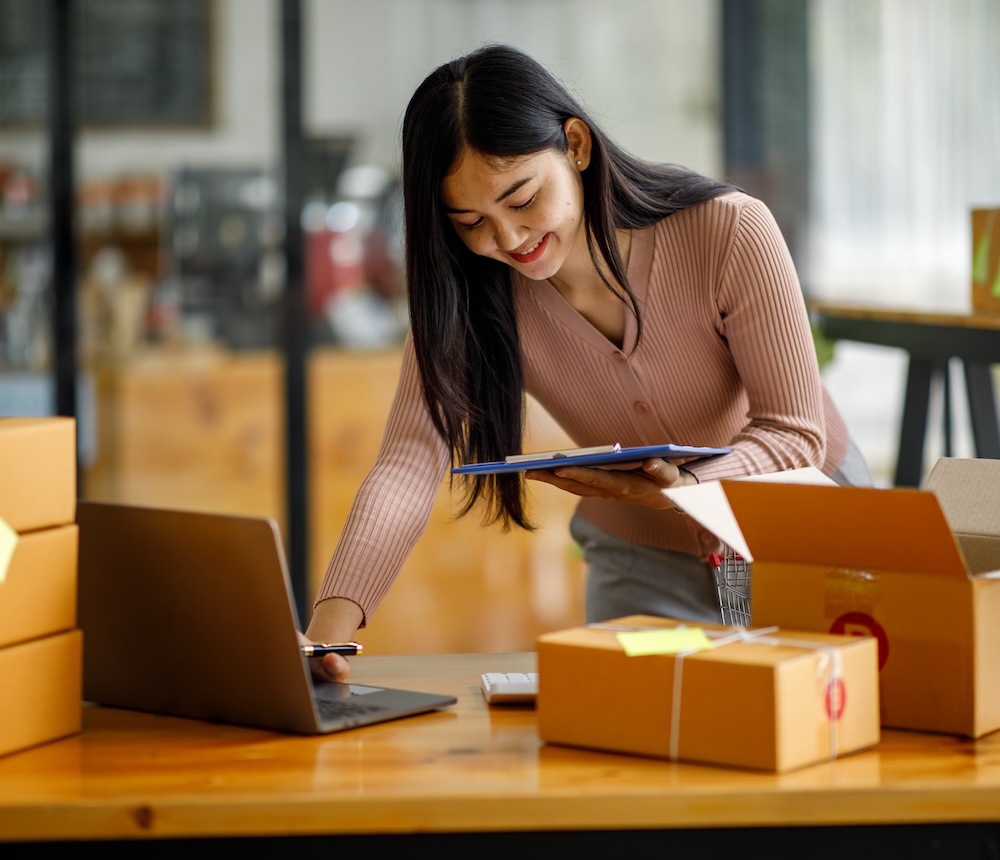 Woman packing ecommerce orders, joyful